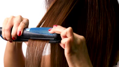 a female using hair crimpers to straighten her own hair