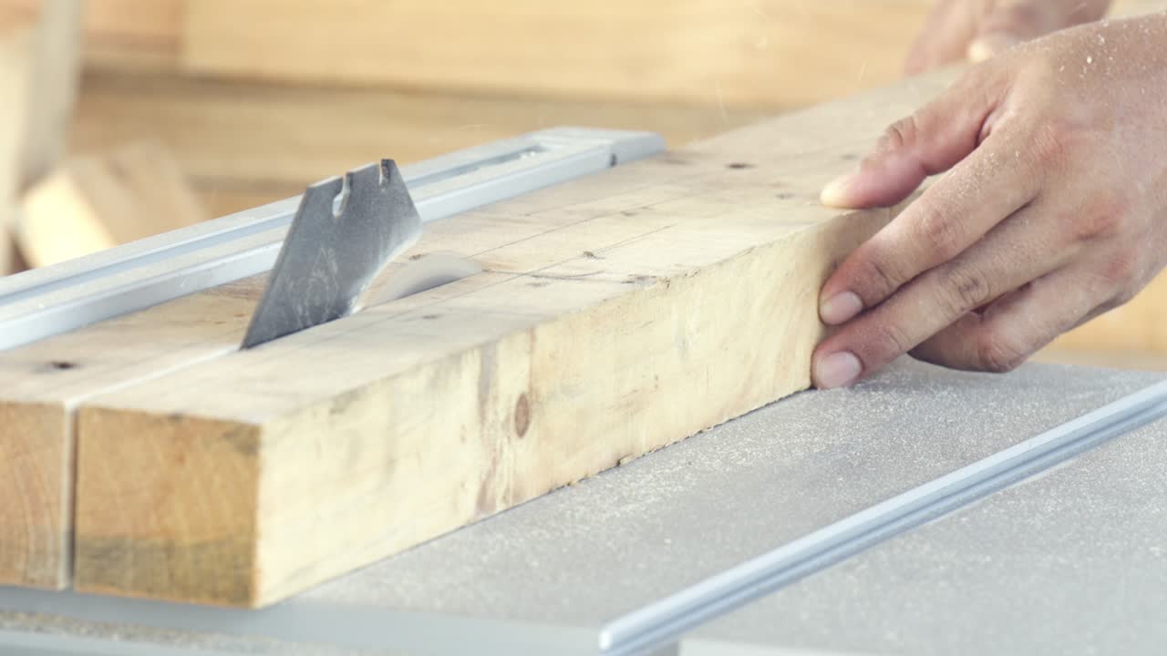 hombre de primer plano carpintero de mano aserrando madera con sierra eléctrica