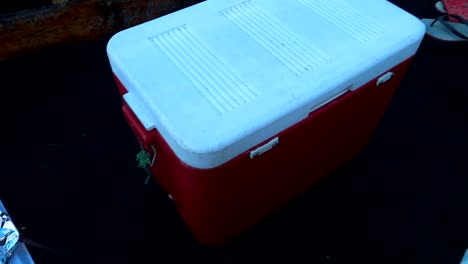 Hand-held-shot-of-a-small-red-cooler-on-a-small-boat-in-Zanzibar,-Tanzania,-Africa