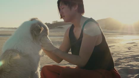 woman loving her dog on the beach at sunset with sun flare