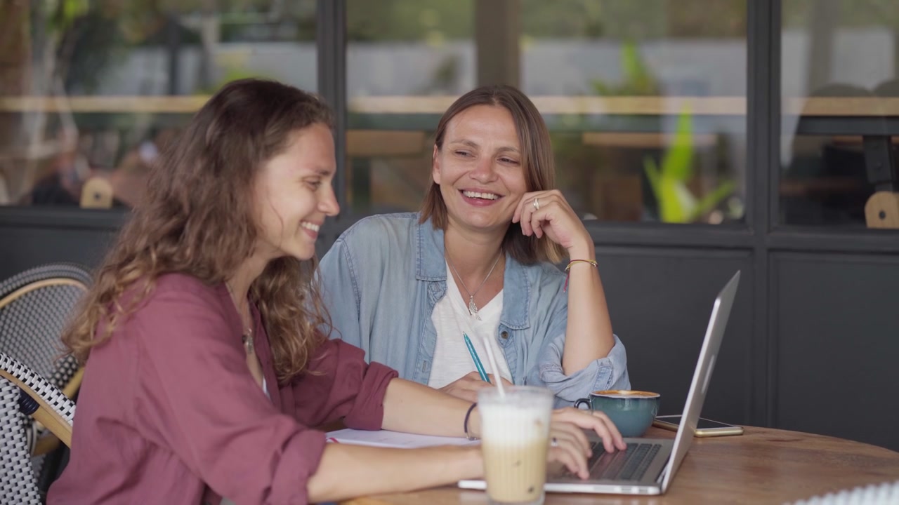 Due donne che collaborano su un laptop in un caffè