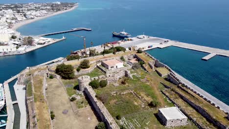 cinematic dron shot revealing harbor and castle ruins in greek island during sunny day