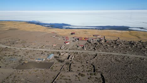 aerial flying backwards from village, salar de uyuni in background, bolivia