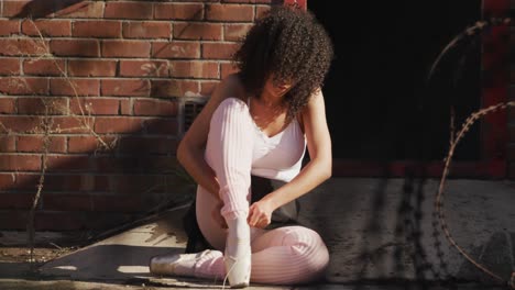 female dancer puts on her ballet shoes on a rooftop