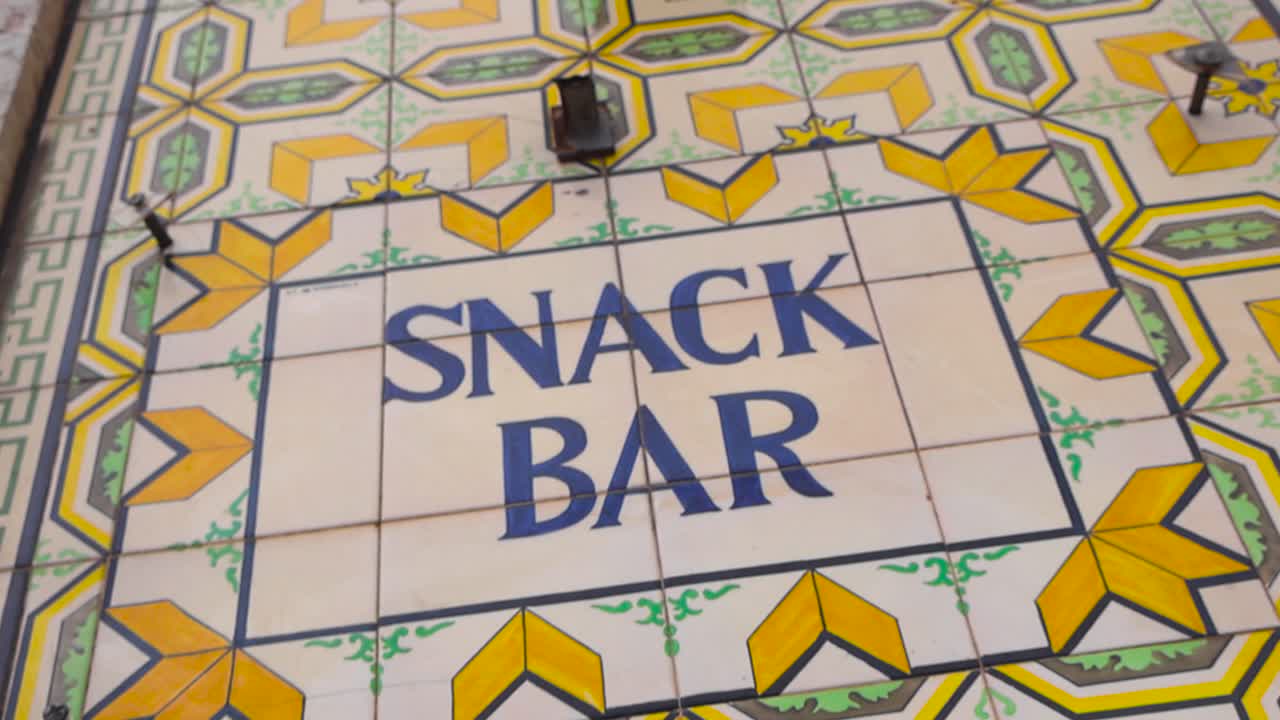 Cinematisk nærbillede af traditionelle portugisiske azulejo-fliser med en farverig Snack Bar-inskription med kunstfærdige geometriske mønstre, filmet i dagslys i Lissabon