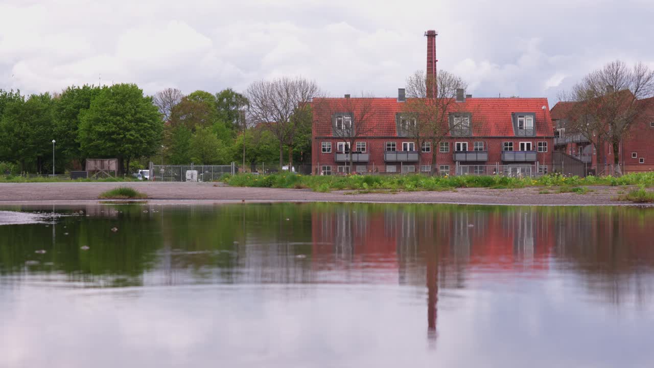 A peaceful lakeside view of residential buildings in Aabenraa, Denmark, with trees