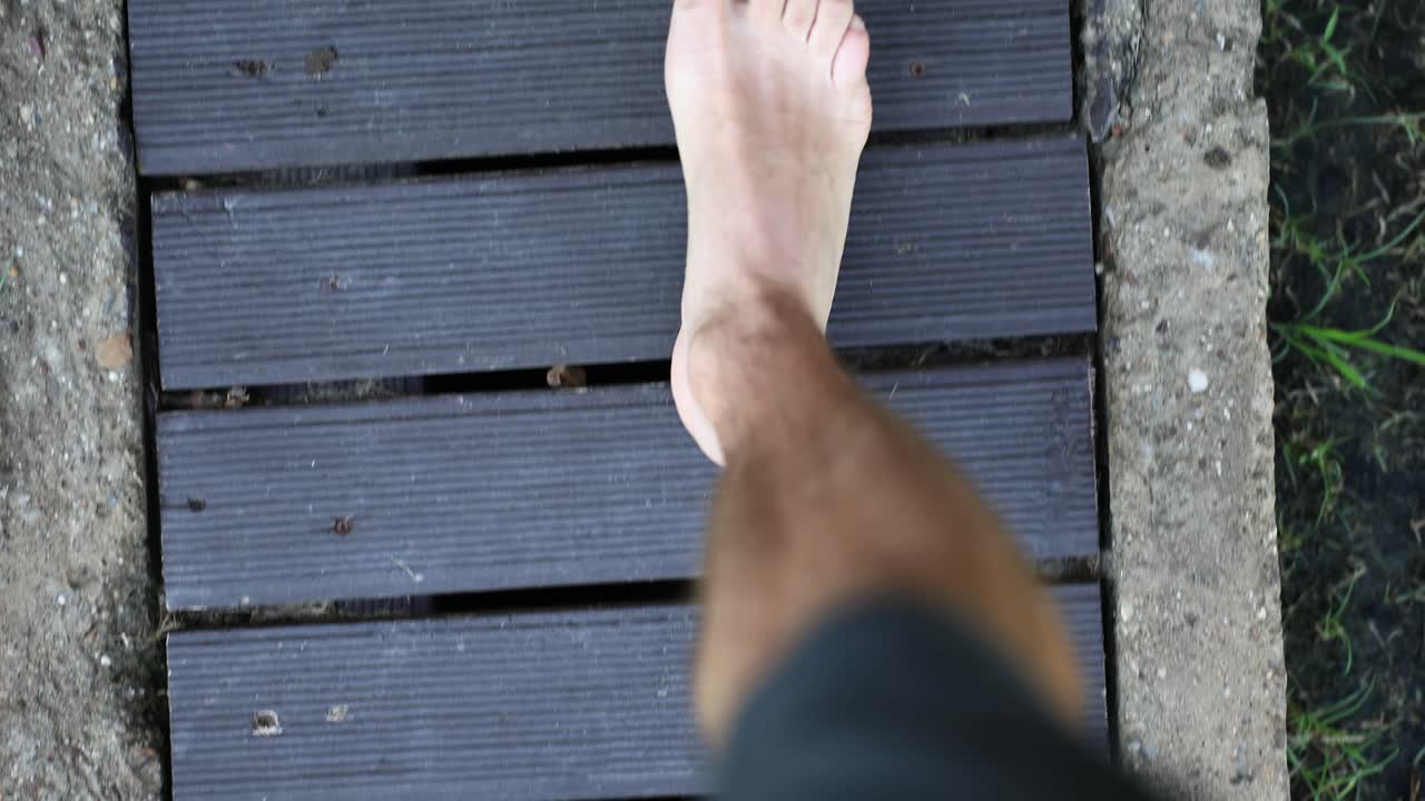 A bare foot walking on a wooden walkway