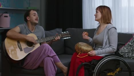 paraplegic woman and cheerful man performing song at home