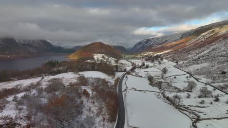 Valley-and-lake-surrounded-by-mountains-with-road-and-very-light-traffic-on-overcast-winter-morning-at-Thirlmere,-English-Lake-District,-Cumbria,-UK