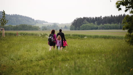 Statische-Fhd-aufnahme-Einer-Familie-Mit-Zwei-Kleinen-Töchtern,-Die-Durch-Eine-Malerische-Landschaft-Von-Dolní-Morava,-Tschechische-Republik,-Mit-Feldern-Und-Wäldern-Ringsum-Wandern