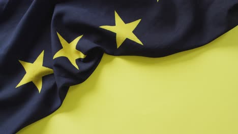 Video-of-creased-flag-of-european-union-lying-on-yellow-background