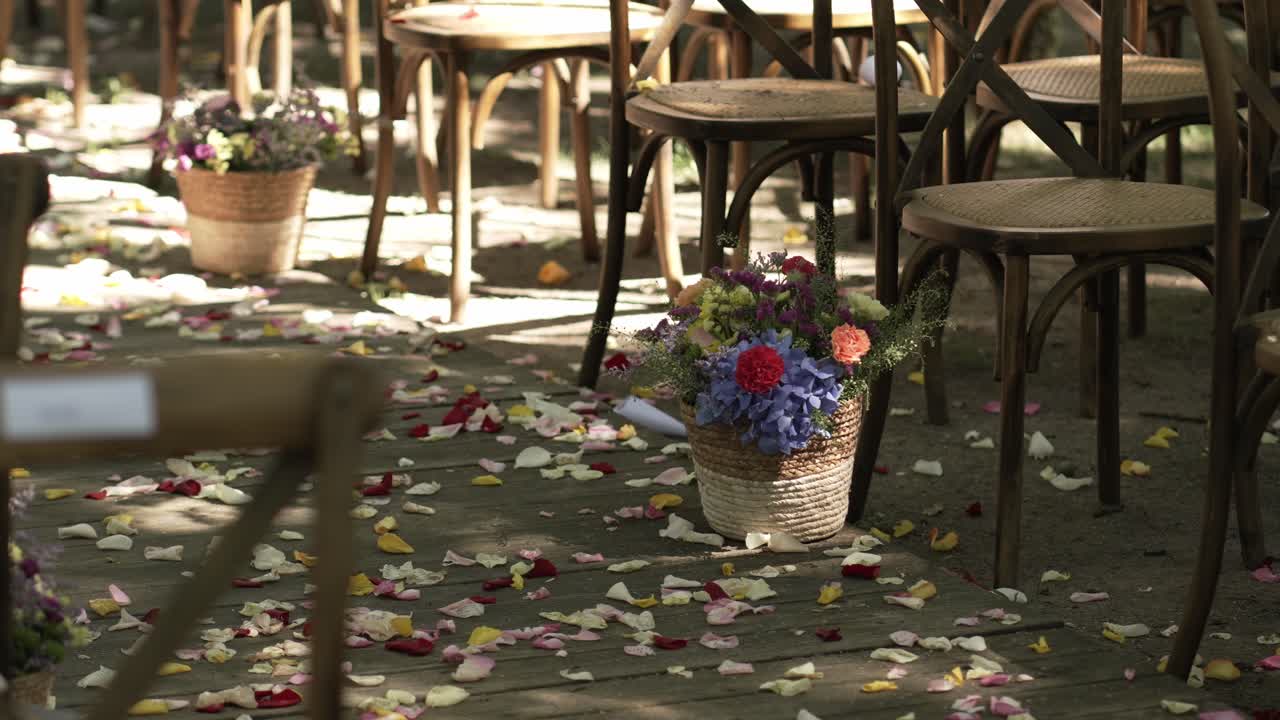wedding ceremony chairs with scattered flower petals and vibrant floral aisle baskets