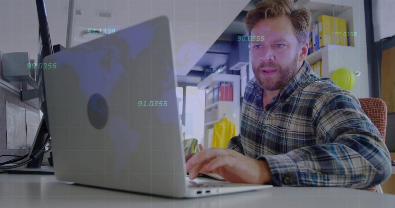 Mann arbeitet im Büro am Laptop mit globaler Datenüberlagerung.
