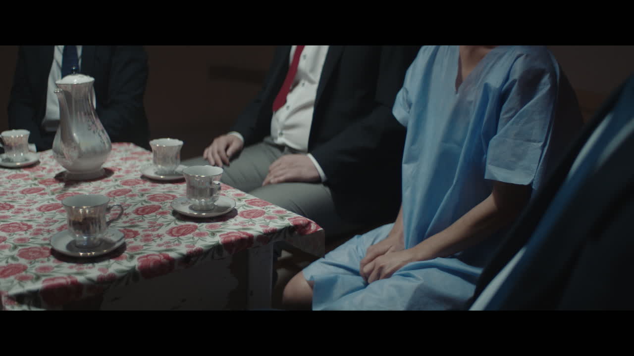 A girl sits at a table with strange figures in animal masks