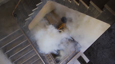 mixed race woman holding white flare walking down the stairs in an empty building