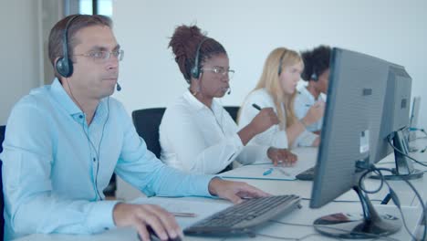 team of call center consultants in headset sitting in row