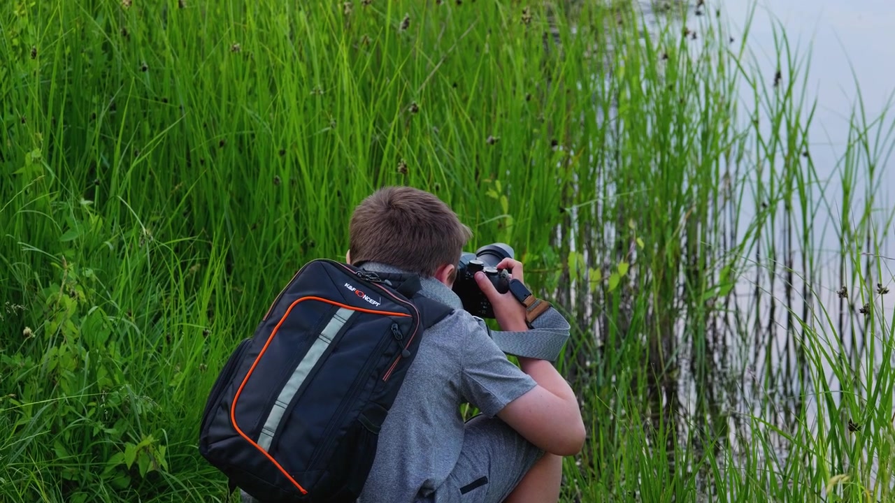Giovane fotografo, con in mano la macchina fotografica, che scatta foto della fauna selvatica e dei paesaggi rurali nel Regno Unito.