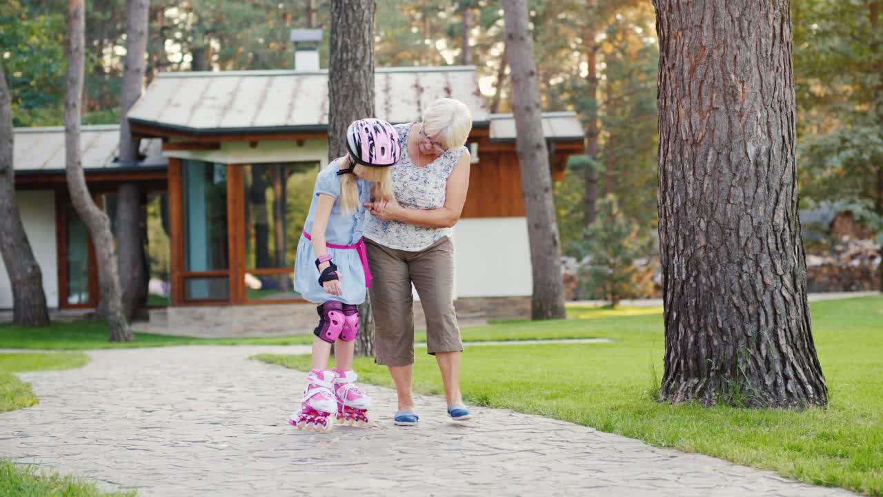 Una donna anziana insegna alla bambina a pattinare sui pattini a rotelle. Anziani attivi. Video 4K.