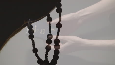 animation of caucasian woman reading bible over hands with rosary