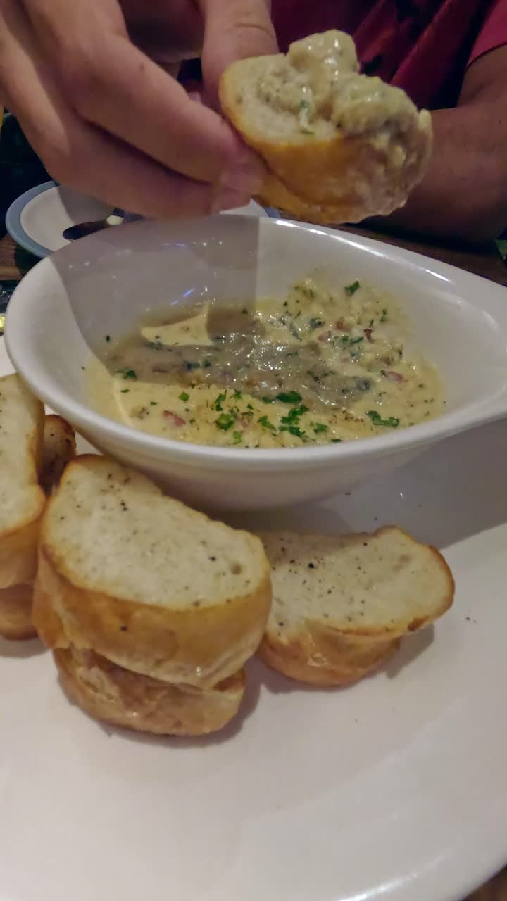 Dipping toasted bread into a creamy cheese fondue, comfort food dish as an appetizer