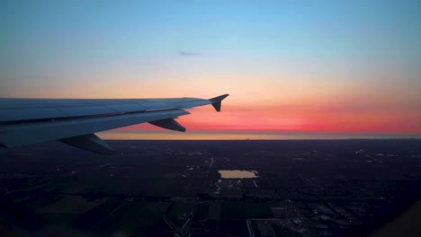 view of airplane wing from window landing in italy during sunset