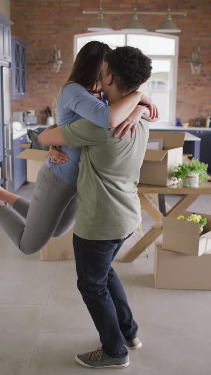 video vertical de una pareja feliz y diversa sonriendo y abrazándose en casa