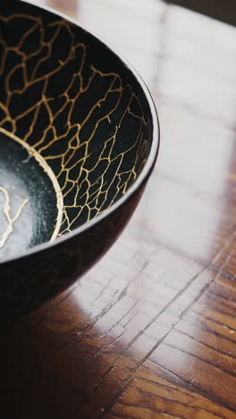 decorative black bowl with gold crackle pattern on wooden table