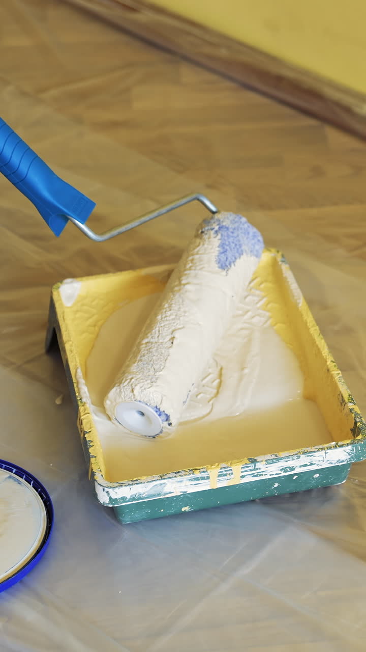 Painter put down roller into paint tray to renovate painting walls. Apartment decorating and home. Construction while renovating and improving. Close-up. Vertical video