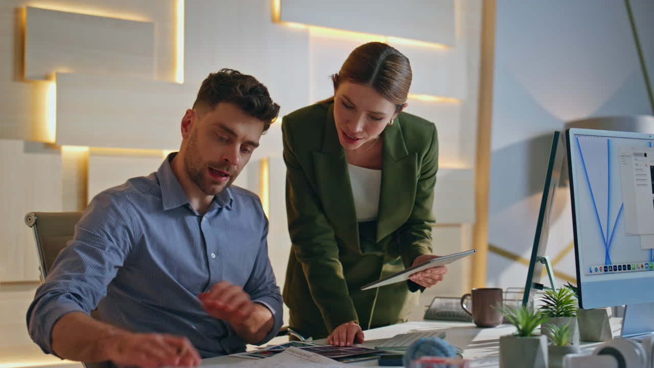 Two colleagues creating project in design studio. Man designer showing paper