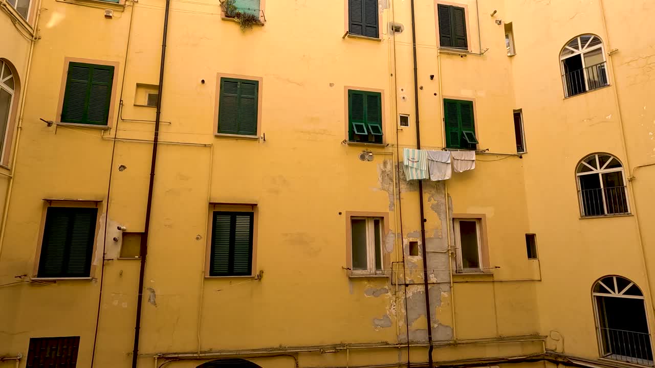 edificio amarillo con persianas y ventanas verdes