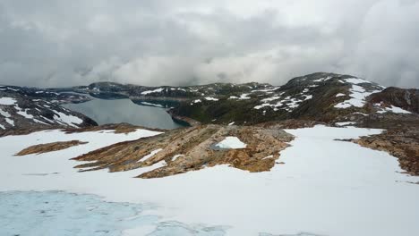 flying over glacier in norwegian mountains towards a lake