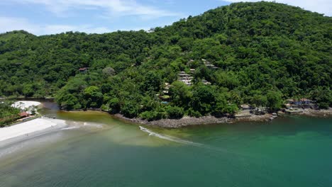 aerial view following a boat driving in to the sahy river in barra do sahy, brazil