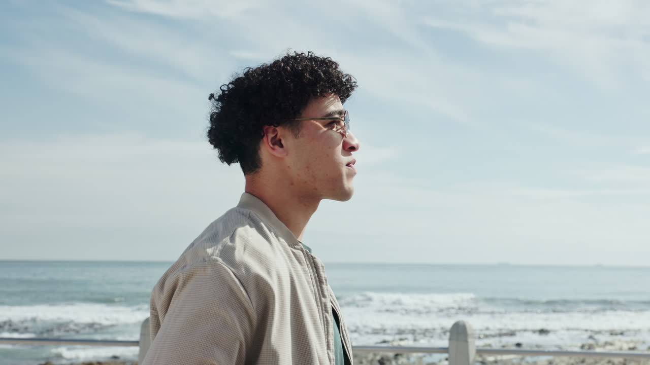Man with curly hair and sunglasses on the beach