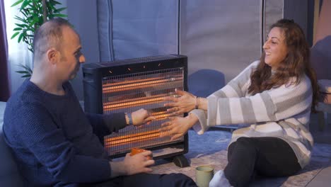 married couple sitting next to electric heater.