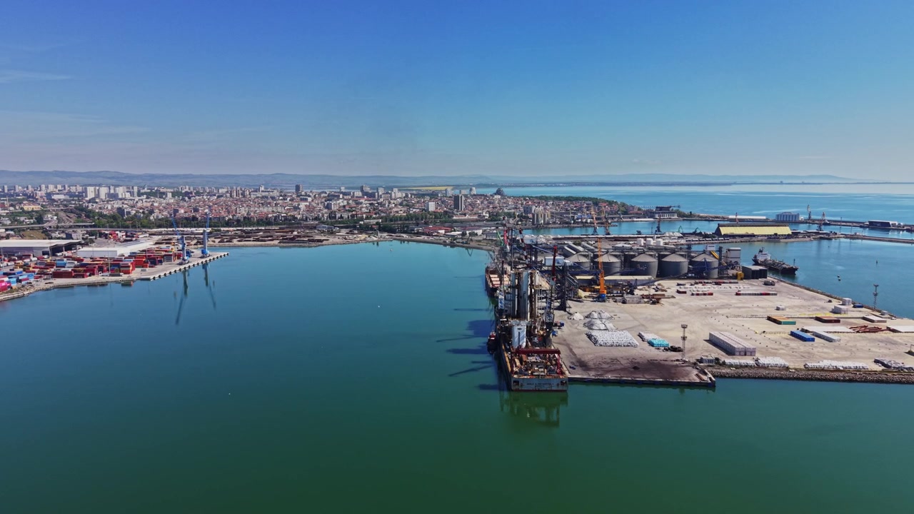 Vista del porto trafficato con lo skyline della città e acqua blu cristallina durante il giorno.