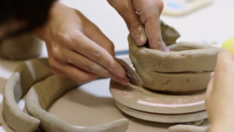 artists joining parts of clay or ceramic work on wheel on a workshop