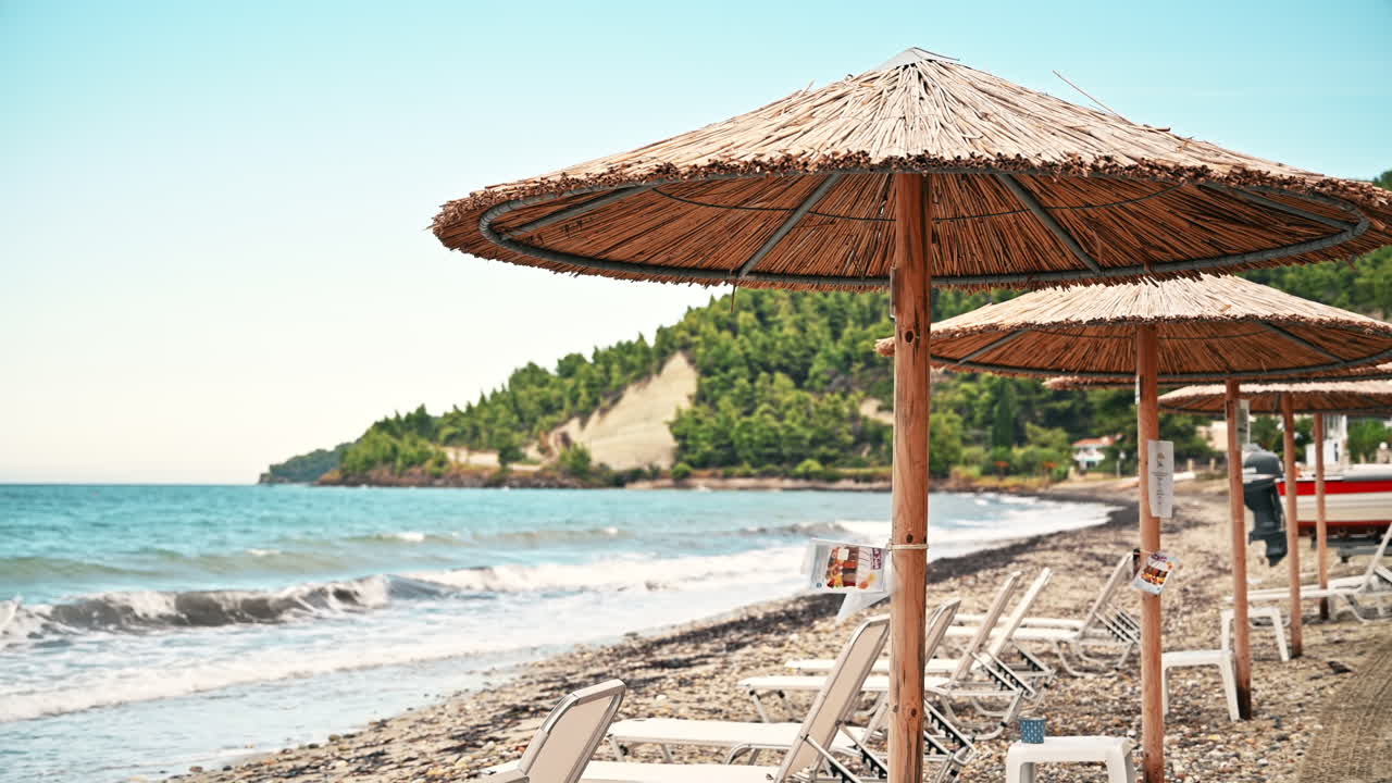 Beach on the aegean coast in Greece. Sunbeds, umbrellas, greenery, blue sea