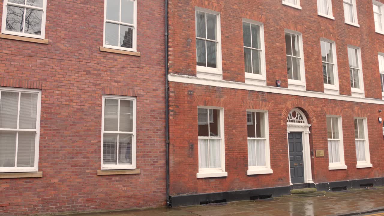 arquitectura de ladrillo de un edificio al lado de una calle húmeda durante un día lluvioso en manchester, inglaterra