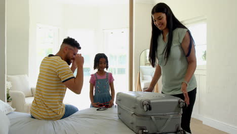 family packing suitcase at home, preparing for vacation with joyful smiles