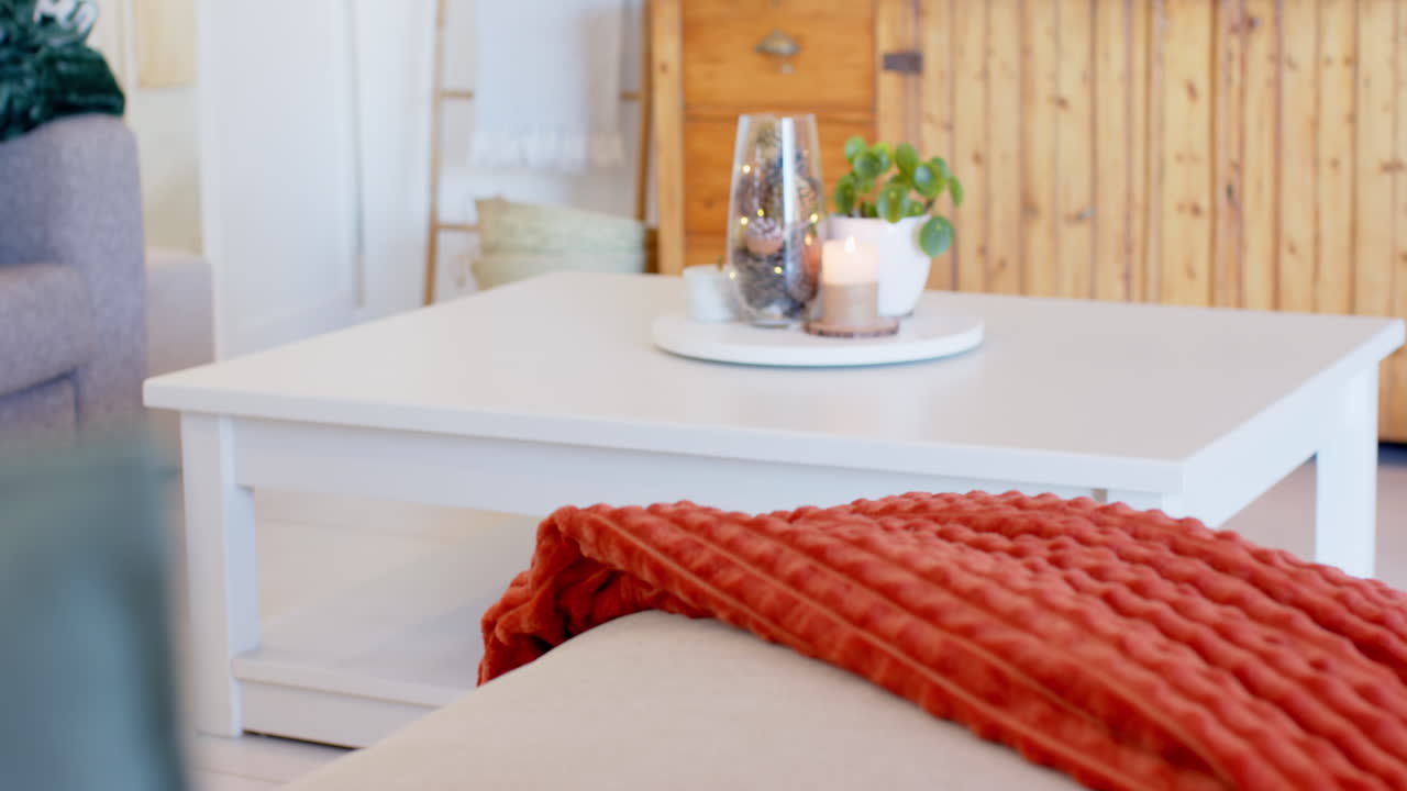 Cozy living room with candlelit table and warm red blanket on sofa, copy space