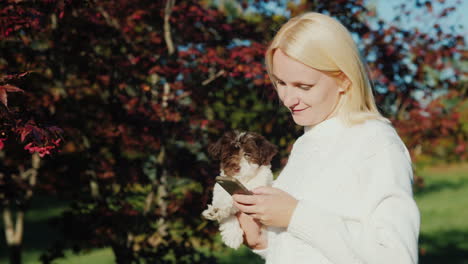Woman-Holding-Puppy-Uses-Phone