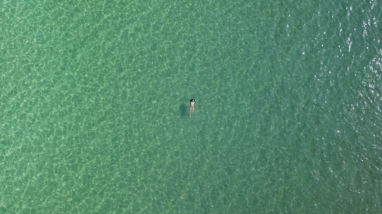 비키니를 입은 젊은 여성이 에게해의 푸른 바다에서 등을 대고 헤엄친다