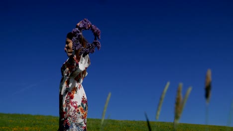 hippie girl with a wreath of flowers on her head goes through the field.