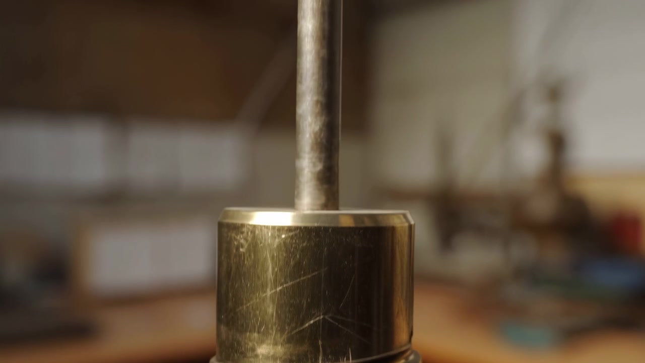 Rotazione di una vite in officina, con una vite metallica su un banco da lavoro in legno, texture del legno, da una prospettiva ravvicinata, con accenti dorati e marroni e un'atmosfera neutra, dettaglio nitido.