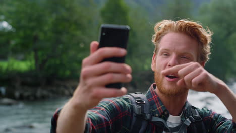 guy using smartphone for video call. emotional hiker gesturing hand at camera