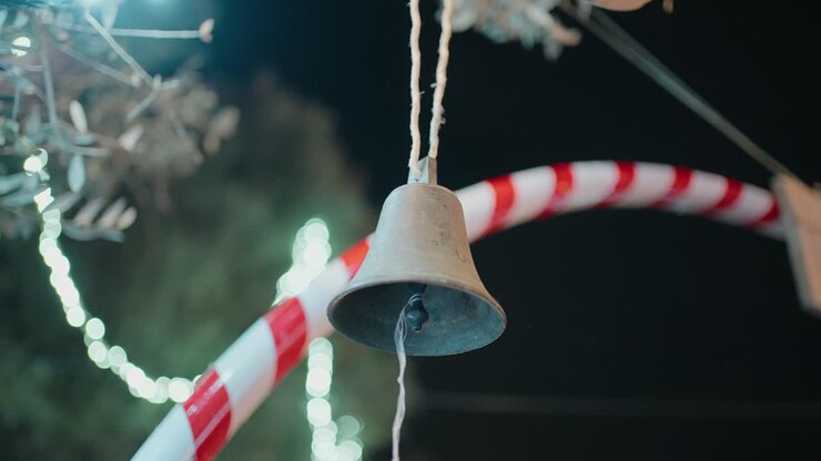Close up of a hanging bell at night surrounded by festive candy cane decorations