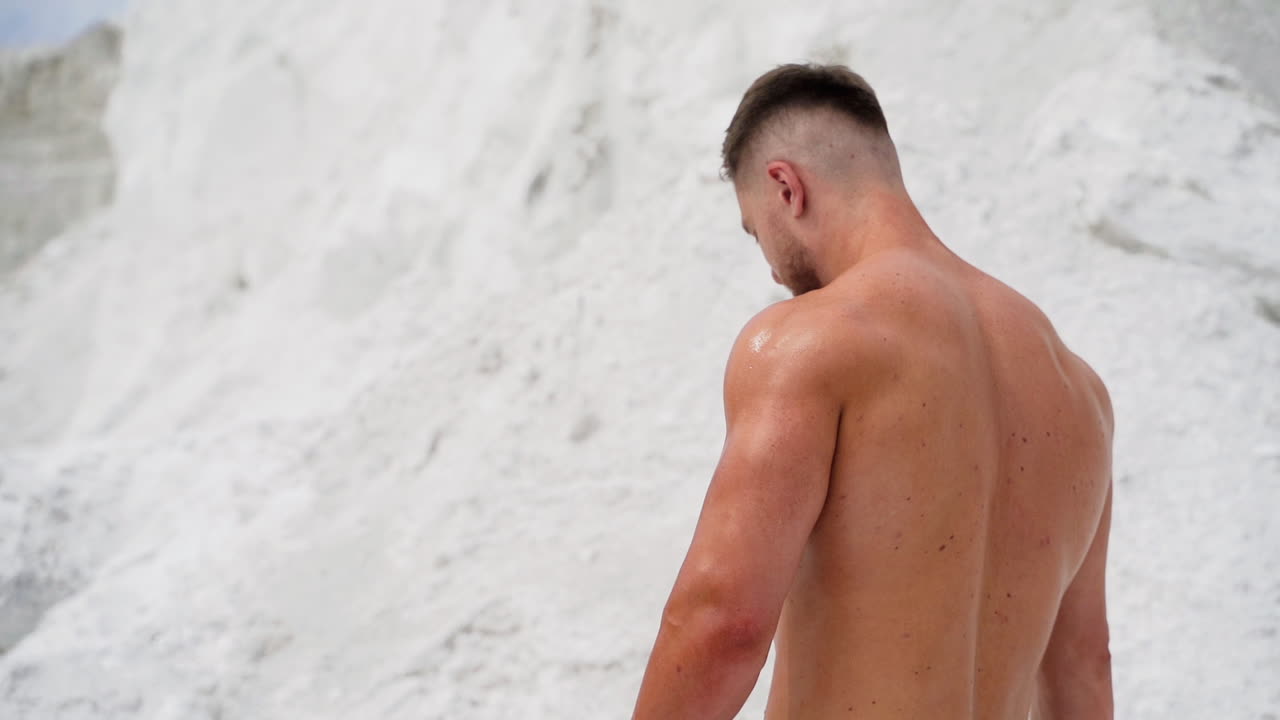 Athletic male resting after work out on nature. Outdoor lifestyle portrait of bodybuilder on natural