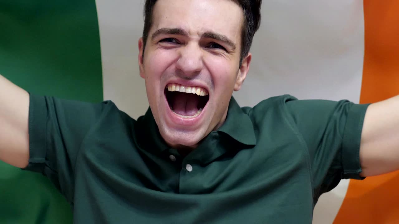 un joven irlandés celebra sosteniendo la bandera de irlanda en cámara lenta