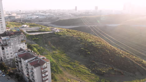 cámara caminando entre las verdes colinas en dirección a nuevos edificios residenciales en el horizonte