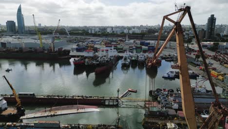 primer plano aéreo de una grúa de carga en el puerto comercial de montevideo, uruguay, con el horizonte de la ciudad en el fondo